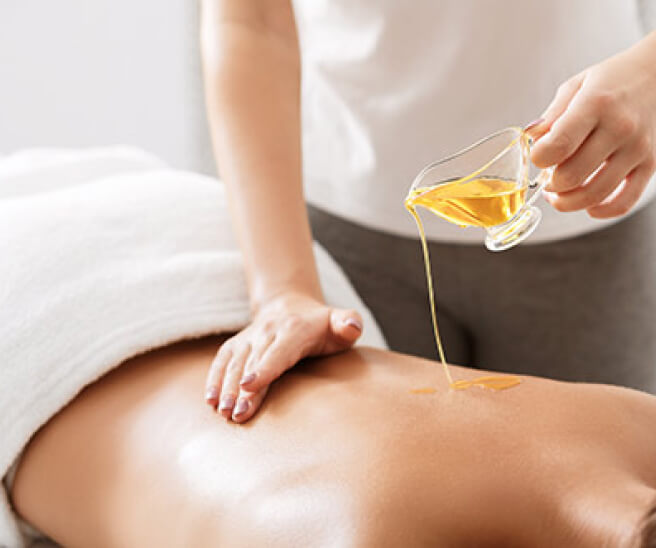 Guest receiving a relaxing in-room back massage at KUDO Hotel with massage oil and spa setup.