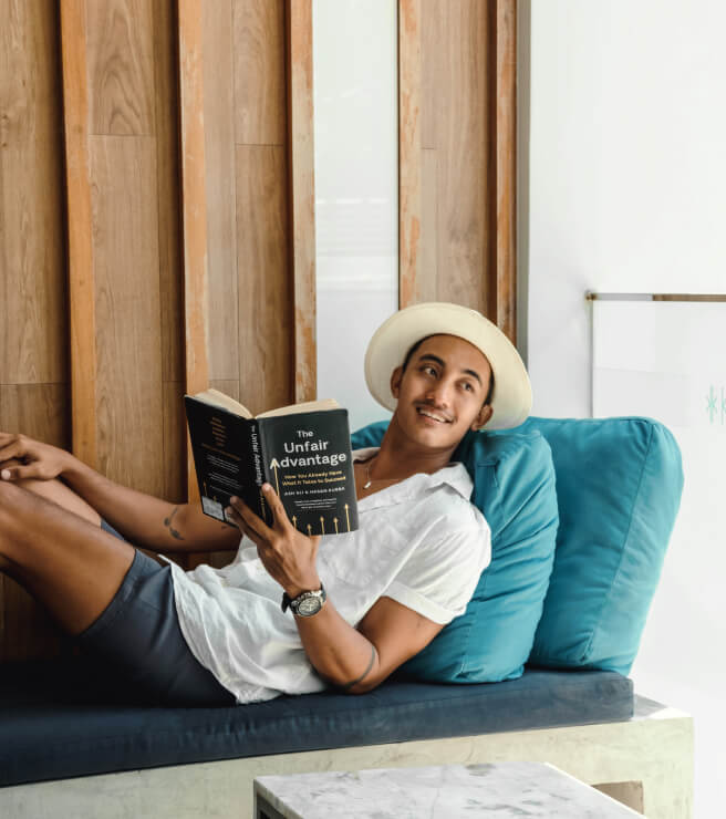 Man in vacation outfit reading on a lounge chair, enjoying a relaxed extended stay with Kudo Hotel’s Stay Longer Special.