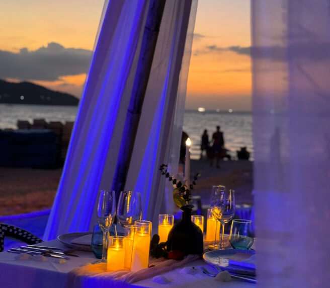 Romantic dinner table setup with candles and elegant décor, creating a cozy and intimate beachside atmosphere